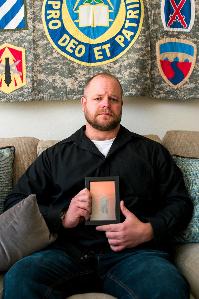 Combat Veteran Aaron Steckman Holds A Photo Of His Fallen Friend