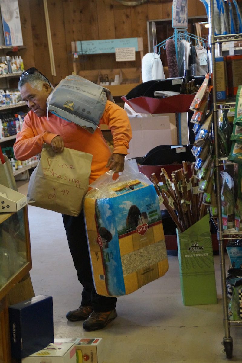 Feed Barn employee Antonio "Leonardo" Orantes helps a customer carry heavy bags on a recent weekend morning. Orantes has worked at the Feed Barn for nearly 12 years. (photo: Bradley Zint)