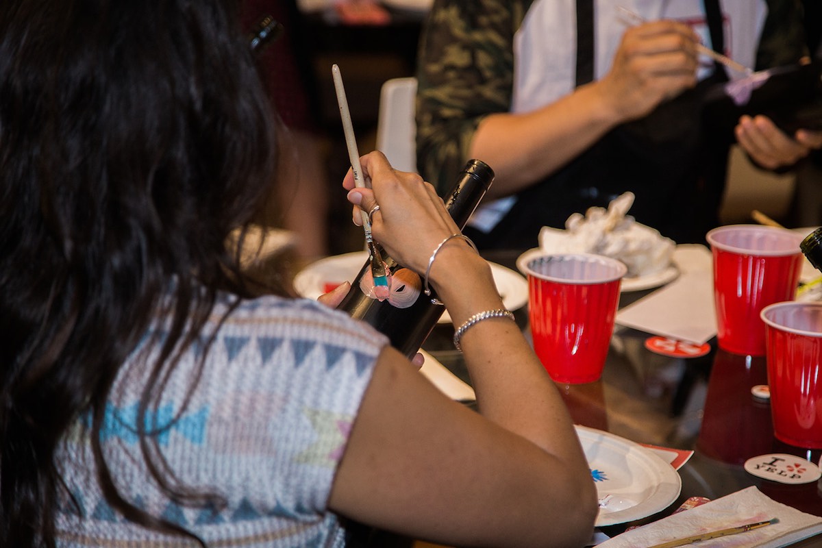 A woman paints a pink flower on a wine bottle at an art class at InspiRED Art Wine in Costa Mesa, California. (photo: Brandy Young)