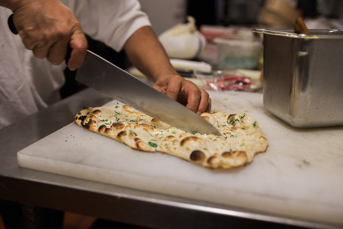 Tilak Rana slices housemade garlic naan at The India Cafe, his restaurant in Costa Mesa, California. (photo: Brandy Young)