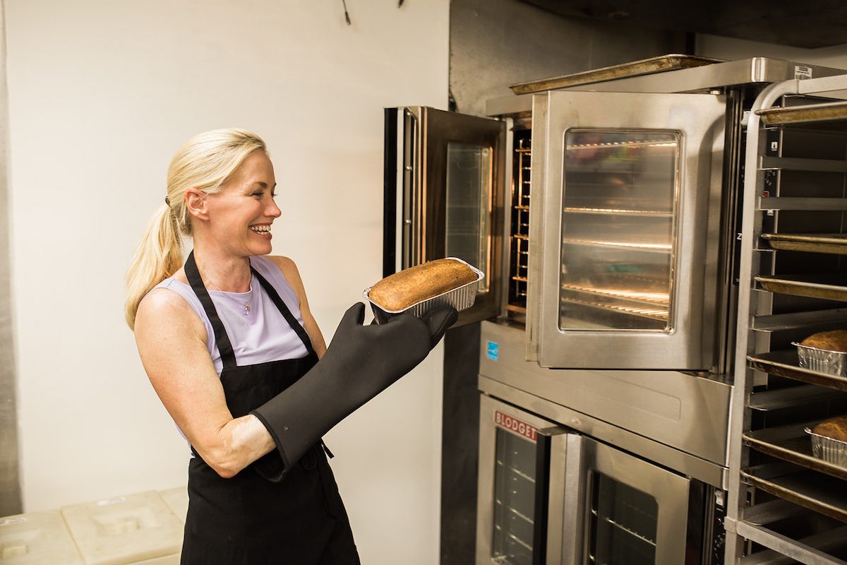 I Heart Costa Mesa: Baker, Christine Bren, pulls a fresh-baked loaf of gluten-free bread out of the oven to cool. At Lavender Lane Baking Co. in Costa Mesa, Orange County, California. (photo: Brandy Young)