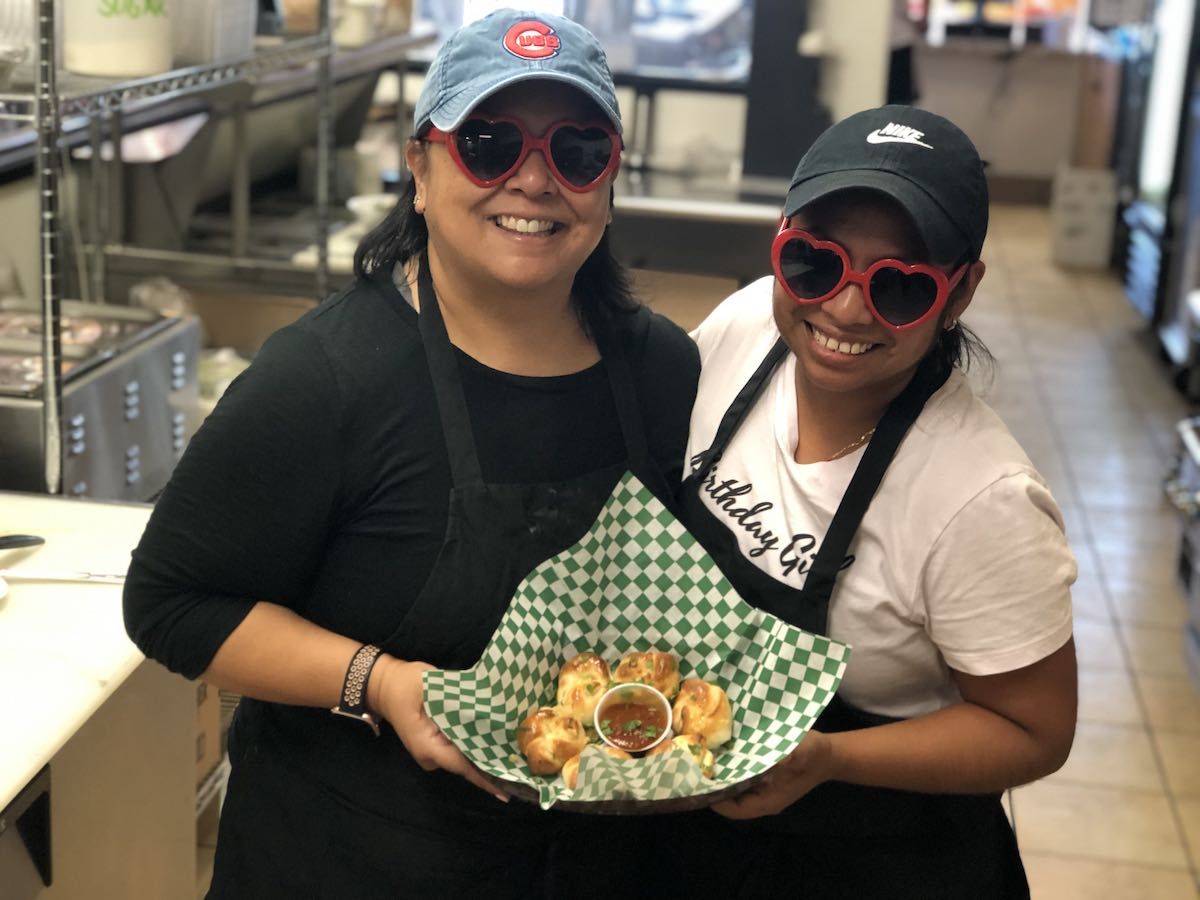I Heart Costa Mesa: Carmina Casso and her employee show off their garlic knots at Ciao! Deli and Pizzeria in Costa Mesa, Orange County, California. (photo: Samantha Chagollan)